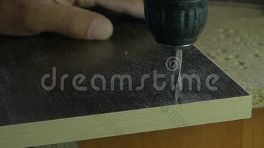 木工杂工使用<strong>电钻</strong>在木工车间台面上木板上打洞.. 钻头钻了个洞